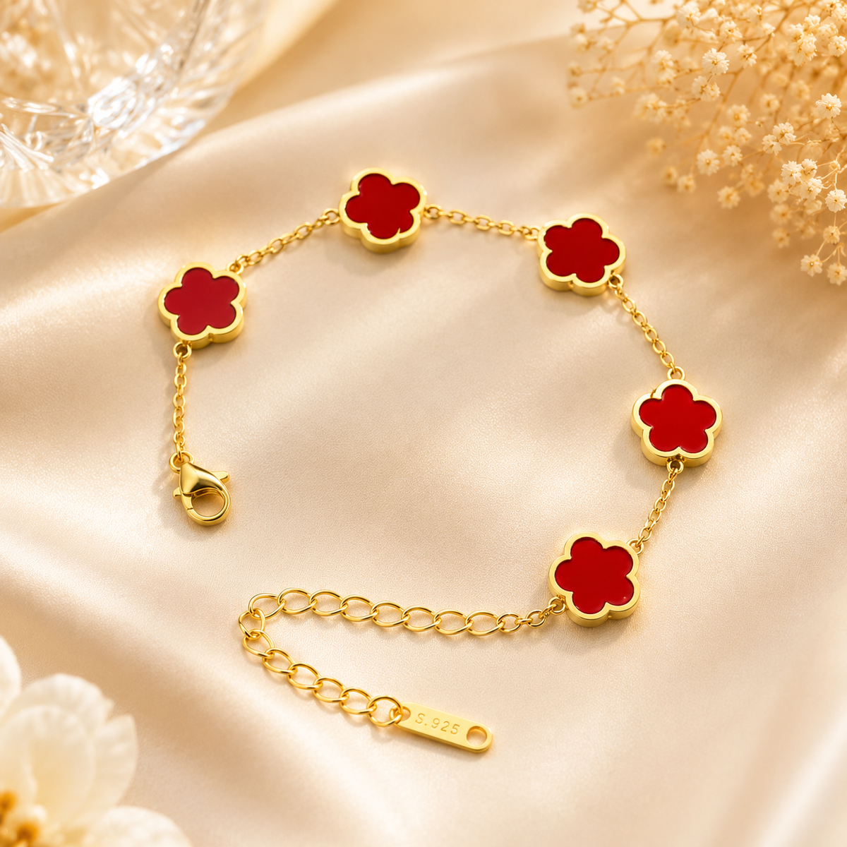 Bracelet à chaîne dorée avec cinq fleurs à pétales rouges.