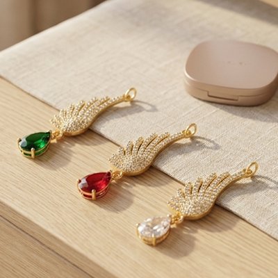 Pendentif collier femme en forme d'aile d'ange dorée orné d'une pierre verte émeraude en forme de goutte.